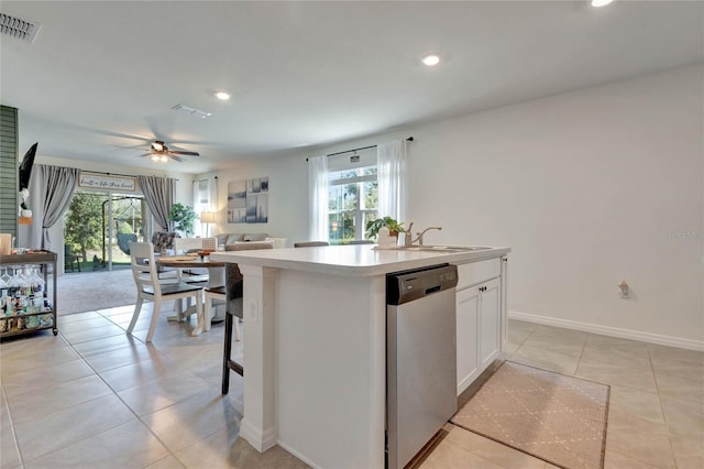 kitchen with ceiling fan, a center island with sink, dishwasher, white cabinetry, and light tile patterned flooring