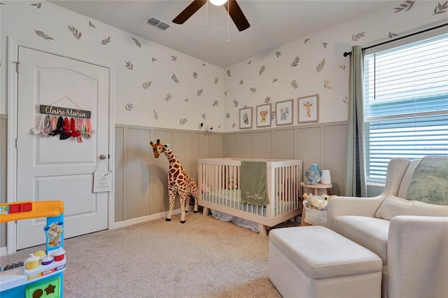 bedroom featuring ceiling fan, carpet floors, multiple windows, and a nursery area