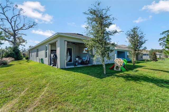 back of house featuring a yard and ceiling fan