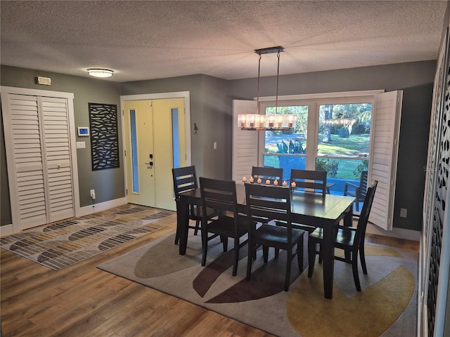 dining space with hardwood / wood-style floors, a notable chandelier, and a textured ceiling