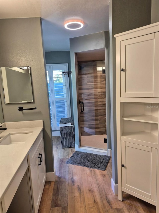 bathroom featuring hardwood / wood-style flooring, vanity, and a shower with door