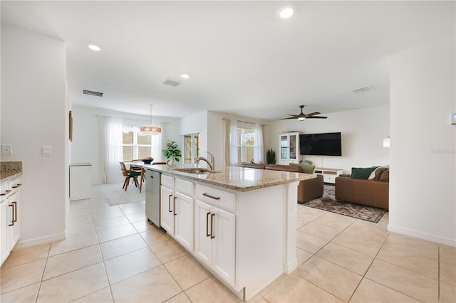 kitchen with light stone counters, stainless steel dishwasher, sink, pendant lighting, and an island with sink