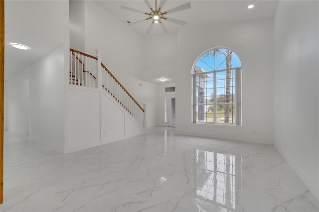 unfurnished living room with ceiling fan and a high ceiling