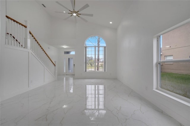 unfurnished living room with ceiling fan and a high ceiling