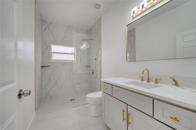 bathroom with toilet, a tile shower, and vanity