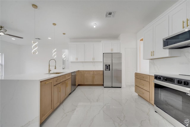 kitchen with white cabinets, stainless steel appliances, sink, hanging light fixtures, and kitchen peninsula