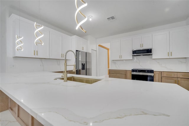 kitchen with pendant lighting, white cabinetry, stainless steel appliances, decorative backsplash, and sink