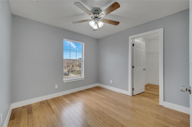 interior space with ceiling fan, a walk in closet, a closet, and light hardwood / wood-style flooring