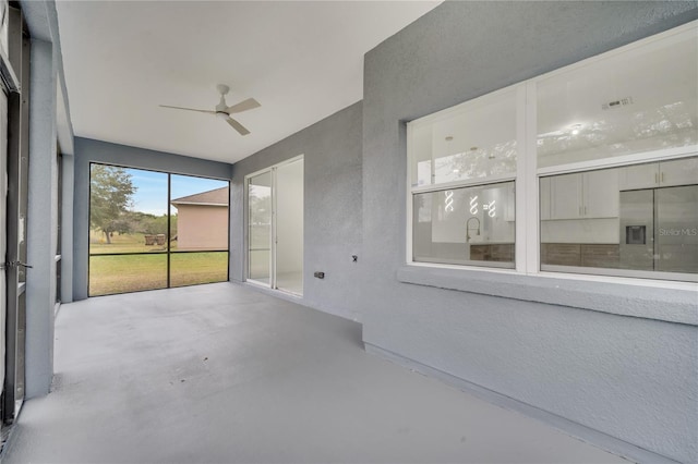 unfurnished sunroom featuring ceiling fan