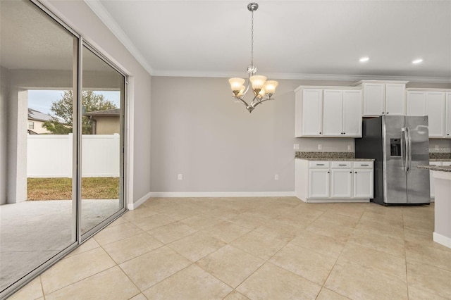 kitchen featuring stainless steel fridge, a wealth of natural light, a notable chandelier, dark stone countertops, and white cabinets