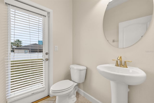 bathroom with toilet, tile patterned floors, and a healthy amount of sunlight