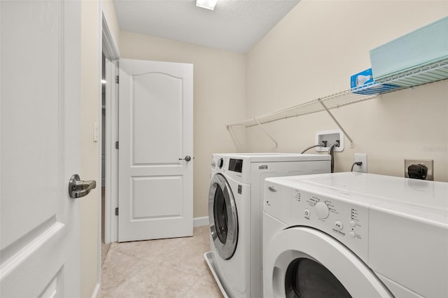 washroom with light tile patterned floors, a textured ceiling, and separate washer and dryer