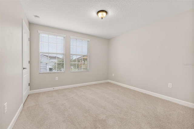 spare room with a textured ceiling and light carpet