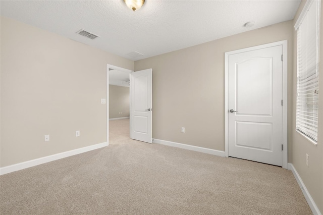 unfurnished bedroom featuring a textured ceiling and light carpet