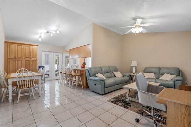 living room with ceiling fan, light tile patterned floors, a textured ceiling, and vaulted ceiling