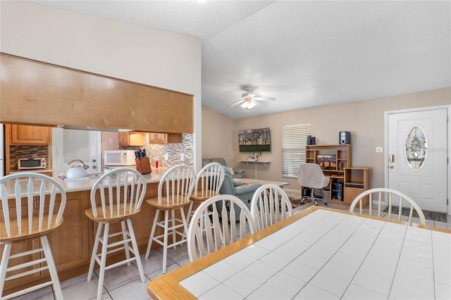 dining room with ceiling fan, light tile patterned flooring, lofted ceiling, and a textured ceiling