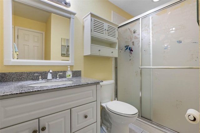 bathroom featuring tile patterned floors, vanity, toilet, and a shower with shower door