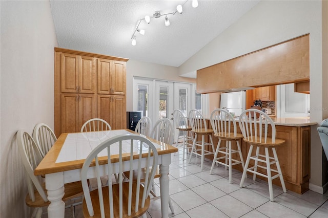 dining area featuring french doors, light tile patterned floors, a textured ceiling, and vaulted ceiling