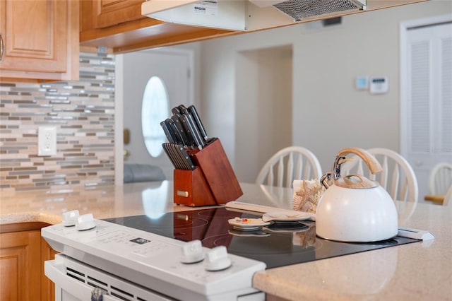 kitchen featuring decorative backsplash, light brown cabinets, and extractor fan