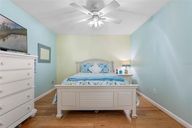 bedroom featuring a textured ceiling, light wood-type flooring, and ceiling fan