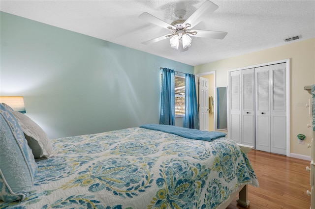 bedroom featuring ceiling fan, wood-type flooring, a textured ceiling, and a closet