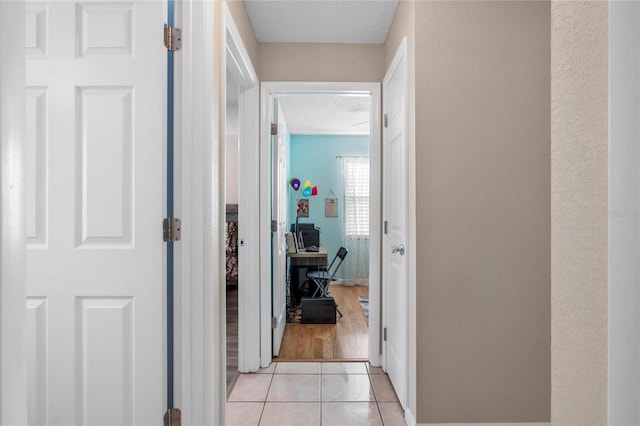 corridor with light tile patterned floors and a textured ceiling