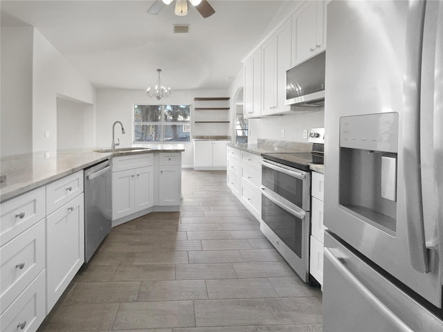 kitchen featuring pendant lighting, white cabinets, sink, appliances with stainless steel finishes, and light stone counters