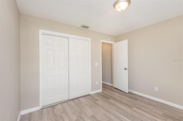 unfurnished bedroom with a closet, a textured ceiling, and light wood-type flooring