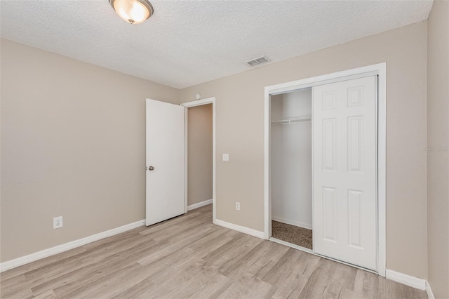 unfurnished bedroom with light hardwood / wood-style floors, a textured ceiling, and a closet