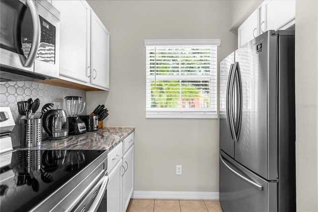 kitchen with white cabinetry, light tile patterned floors, stainless steel appliances, and light stone counters