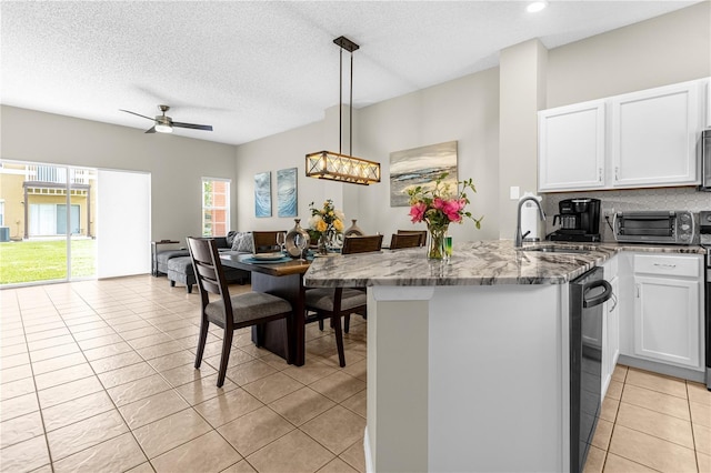 kitchen with kitchen peninsula, dark stone counters, light tile patterned floors, white cabinets, and hanging light fixtures