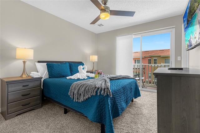 carpeted bedroom featuring ceiling fan and a textured ceiling