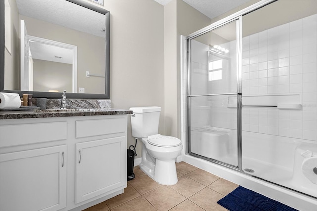 bathroom with tile patterned flooring, vanity, toilet, and a shower with door