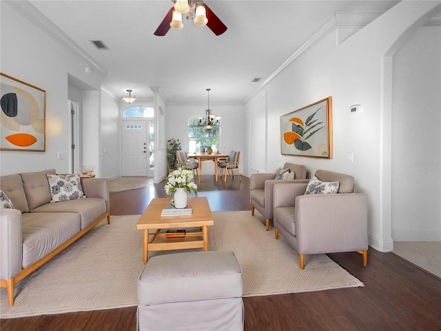 living room with ceiling fan with notable chandelier, ornamental molding, and dark wood-type flooring