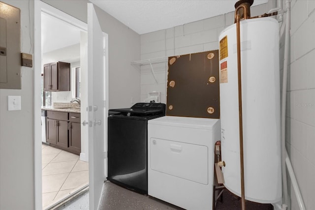 clothes washing area featuring water heater, electric panel, washer and dryer, and sink