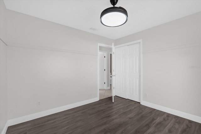 unfurnished bedroom with a closet and dark hardwood / wood-style floors