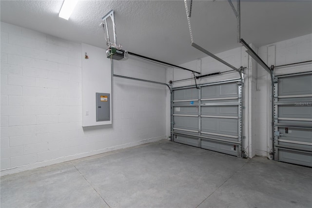 garage featuring concrete block wall, electric panel, and a garage door opener