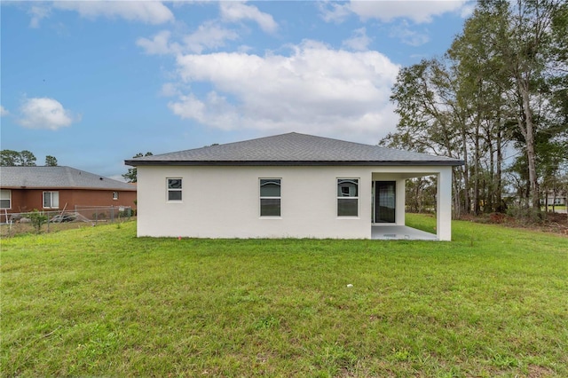 back of house with a patio, a lawn, fence, and stucco siding