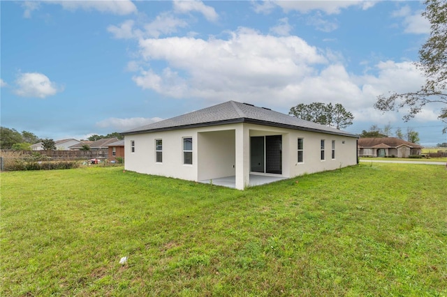 back of property featuring a yard, a patio area, and stucco siding