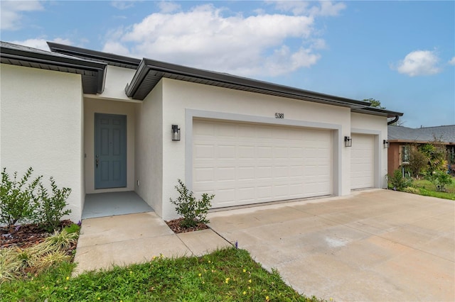 view of front of home with driveway, an attached garage, and stucco siding