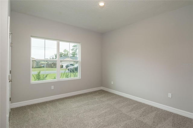 spare room featuring carpet floors, a textured ceiling, and baseboards