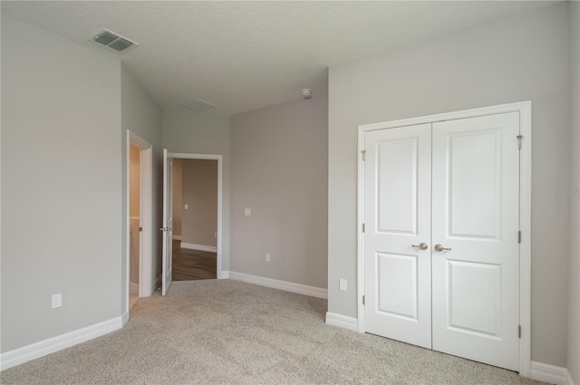 unfurnished bedroom with light carpet, baseboards, visible vents, and a closet