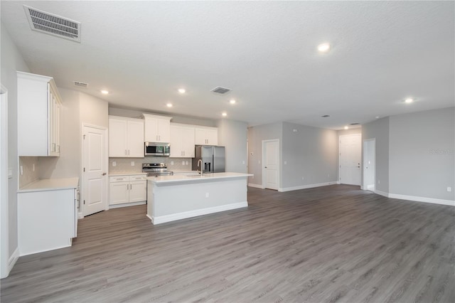 kitchen featuring stainless steel appliances, visible vents, light countertops, open floor plan, and a kitchen island with sink