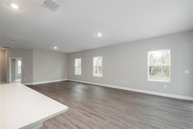 unfurnished living room featuring recessed lighting, wood finished floors, visible vents, and baseboards