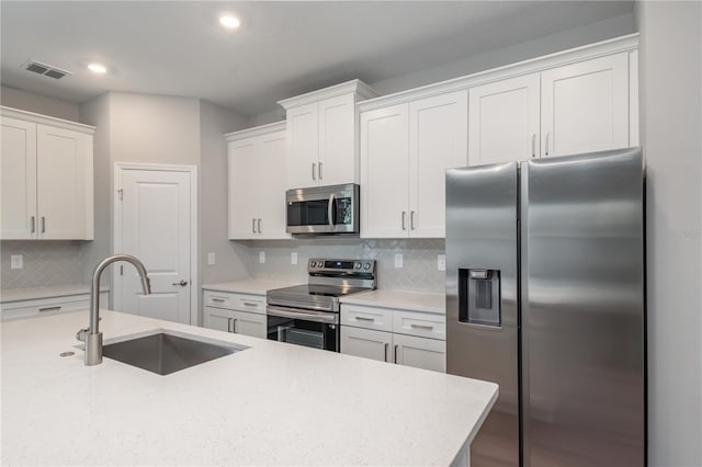 kitchen featuring light countertops, appliances with stainless steel finishes, a sink, and white cabinets