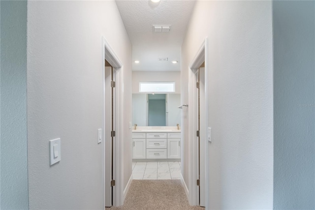 hall featuring visible vents and light colored carpet