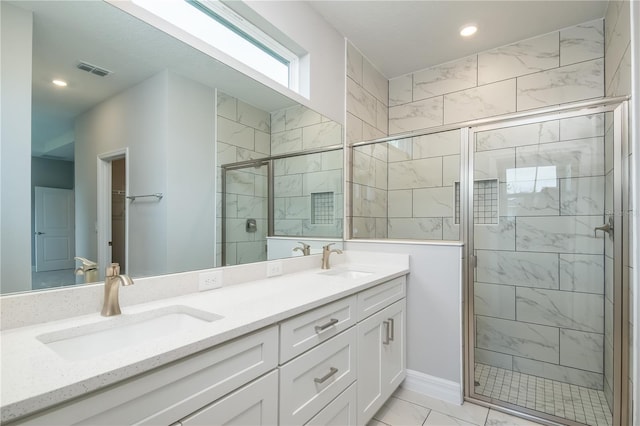 full bathroom with visible vents, a sink, a shower stall, and double vanity