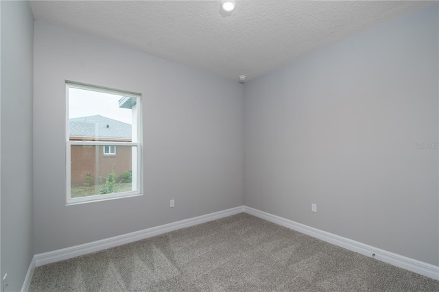 carpeted spare room with a textured ceiling and baseboards