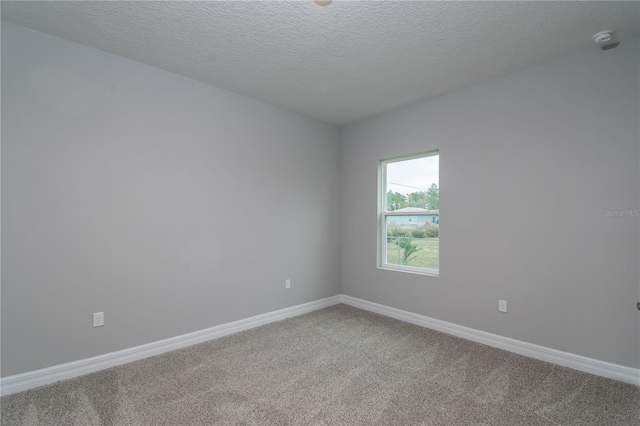 carpeted empty room with a textured ceiling and baseboards