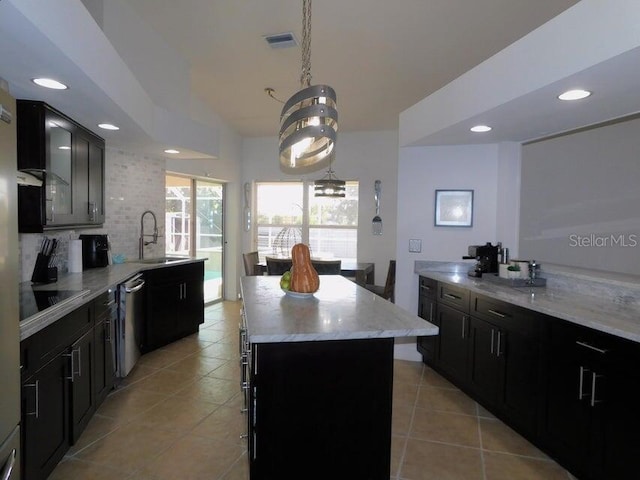 kitchen featuring sink, backsplash, hanging light fixtures, a center island, and black electric cooktop